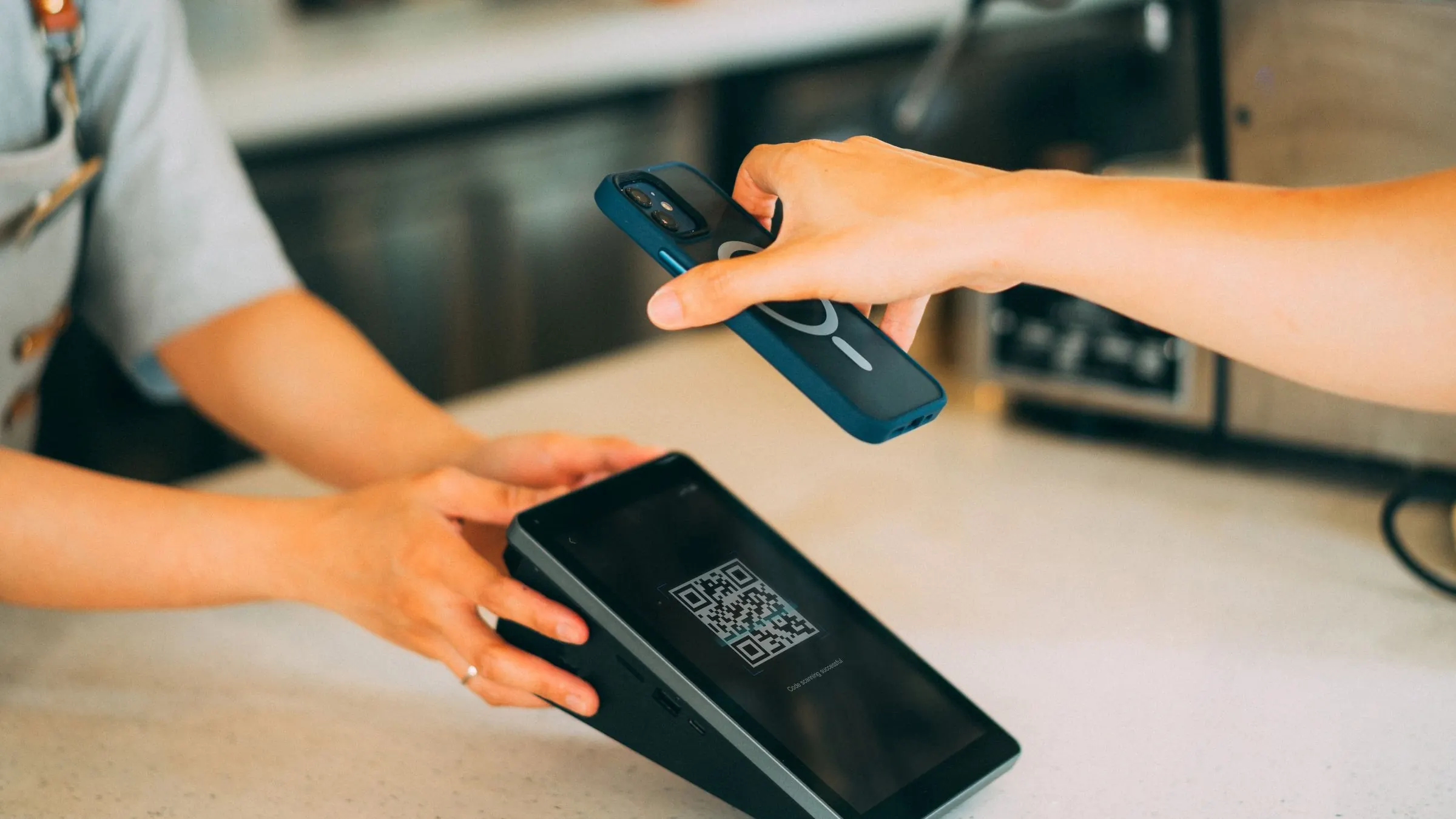 A customer scanning a QR code at a shop counter.